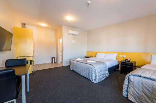 a hotel room with two beds and a desk at C-Motel in Christchurch