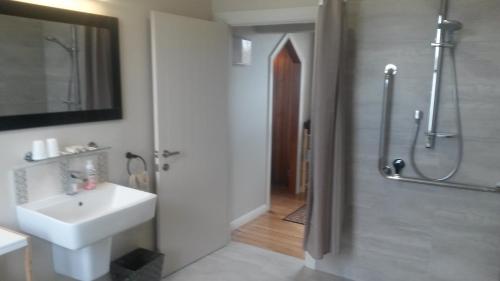 a white bathroom with a sink and a shower at St Andrews Church Nave in Ophir