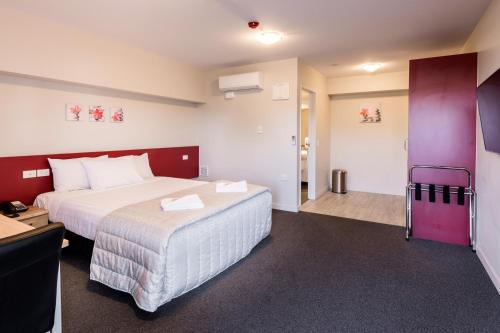 a hotel room with a large bed and a desk at C-Motel in Christchurch