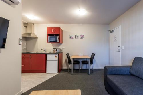 cocina y sala de estar con sofá y mesa en C-Motel, en Christchurch