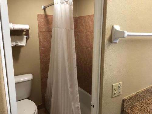a bathroom with a shower with a white shower curtain at La Bella Inn in Tavares