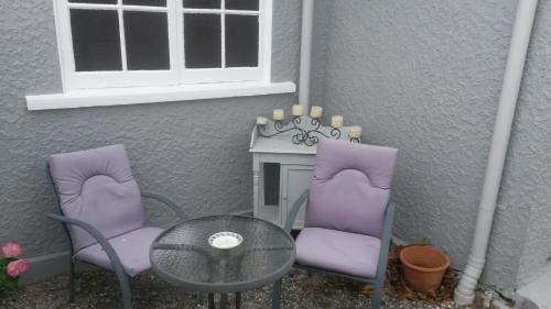 two purple chairs and a table and a window at St Andrews Church Vestry in Ophir