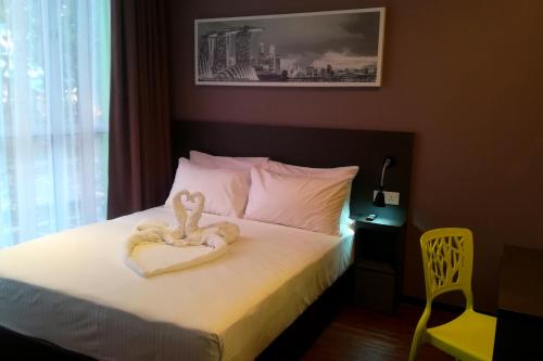 a bed with a stuffed teddy bear sitting on top of it at The Loft Plaza Hotel in Bangi