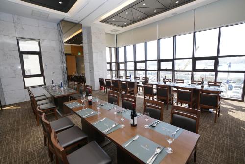 a dining room with tables and chairs and windows at Sea Cruise Hotel in Sokcho