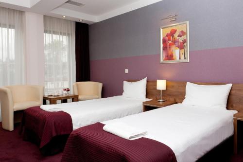 two beds in a hotel room with purple walls at Hotel Swing in Kraków