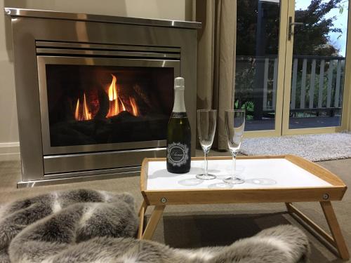 a bottle of wine and two glasses on a table in front of a fireplace at Emerald Ridge in Emerald