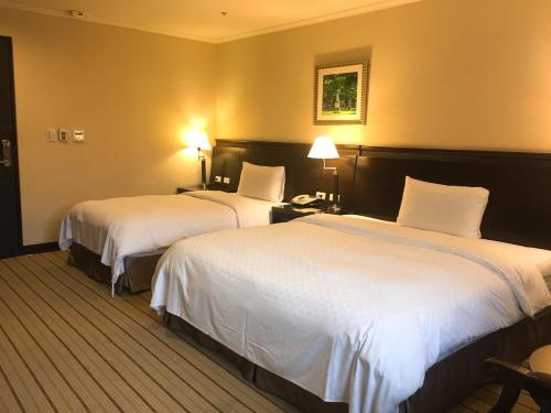 two beds in a hotel room with white sheets at Chong Yu Hotel in Taoyuan