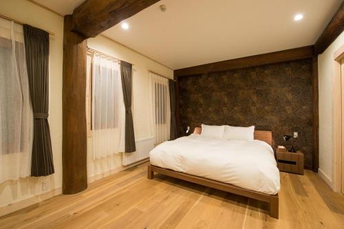 - une chambre avec un grand lit blanc et du parquet dans l'établissement Koho, à Niseko