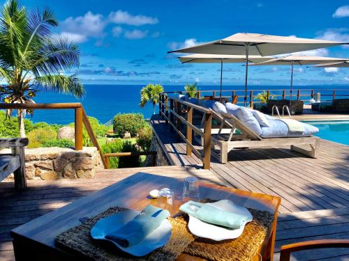 a wooden deck with a table and an umbrella at Château de feuilles & SPA - Praslin island in Baie Sainte Anne