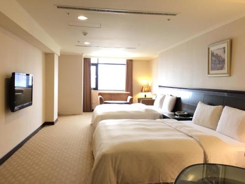 a hotel room with two beds and a television at Chong Yu Hotel in Taoyuan