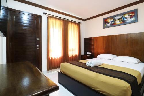 a bedroom with a bed with a wooden headboard and a table at Pondok 3 Mertha in Kuta