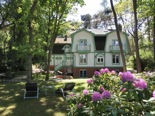 una casa grande con un patio con flores púrpuras en Landhaus Victoria, en Boltenhagen