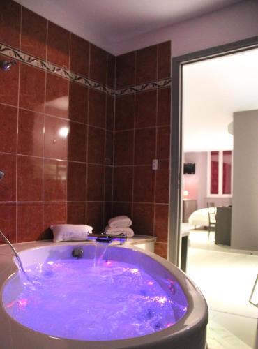 La salle de bains est pourvue d'une baignoire avec une teinte violette. dans l'établissement Hotel-Restaurant des Voyageurs, au Cheylard