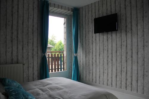a bedroom with a bed and a window with a television at juste pour le plaisir in Saint-Pierre-dʼAlbigny