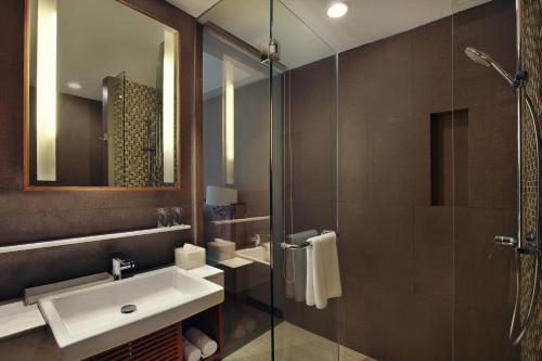 a bathroom with a sink and a shower with a mirror at Mercure Bali Legian in Legian