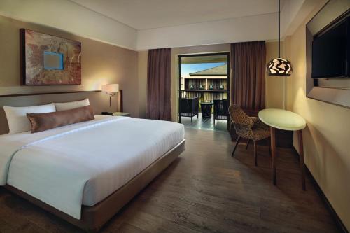 a hotel room with a large bed and a table at Mercure Bali Legian in Legian