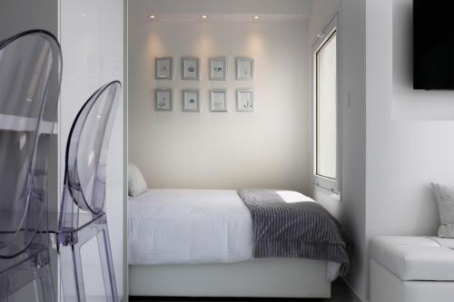 a white bedroom with a bed and a window at The White Pearl Suite - beach front city centre with sea view. in Limassol