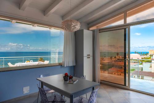 a dining room with a table and a view of the ocean at Terraces d'Orlando - Family Apartments with Sea View and Pool in Capo dʼOrlando