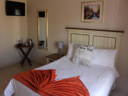 a bedroom with a white bed with white pillows at Divine Guest Lodge in Rustenburg