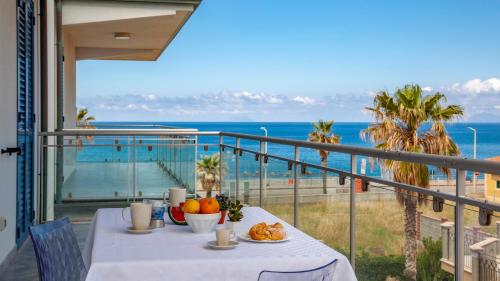 a table on a balcony with a view of the ocean at Terraces d'Orlando - Family Apartments with Sea View and Pool in Capo dʼOrlando