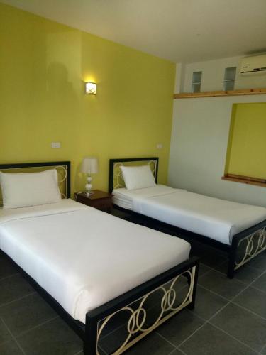 two beds in a room with green walls at Baan Jaru in Chiang Rai