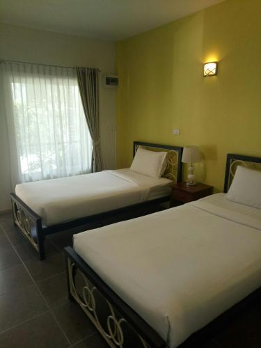 a hotel room with two beds and a window at Baan Jaru in Chiang Rai
