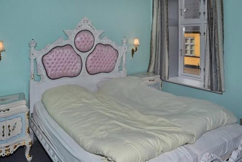 a bedroom with a white bed with a pink headboard and a window at Motel Lido in Bredebro