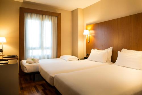 a hotel room with two beds and a window at Sercotel AB Arganda in Arganda del Rey