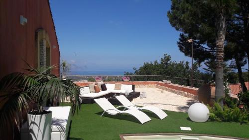 a patio with white chairs and a table on grass at Casa Bonifato in Alcamo