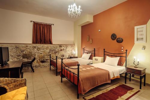 a bedroom with two beds and a desk and a television at Mouzaliko Guesthouse Mansion in Kambos
