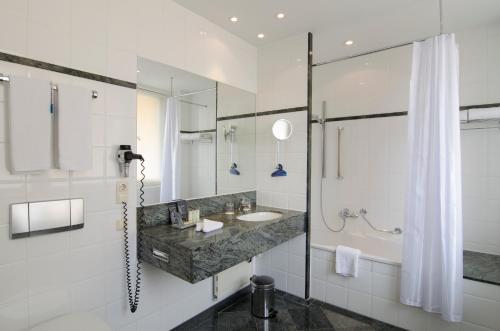 a bathroom with a sink and a shower and a tub at Radisson Blu Hotel Schwarzer Bock Wiesbaden in Wiesbaden