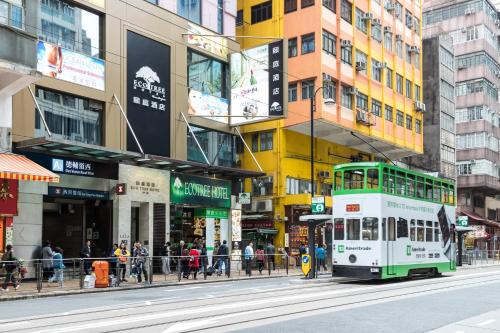 a double decker bus driving down a city street at Eco Tree Hotel Sheung Wan in Hong Kong