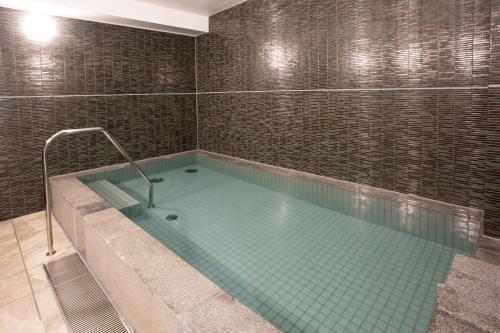 a large swimming pool in a room with a tiled wall at Kuretake Inn Premium Nagoya Nayabashi in Nagoya