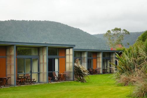 a row of houses with tables and chairs in the grass at Sunset Motel in Fox Glacier