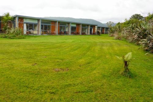 a house with a large lawn in front of it at Sunset Motel in Fox Glacier