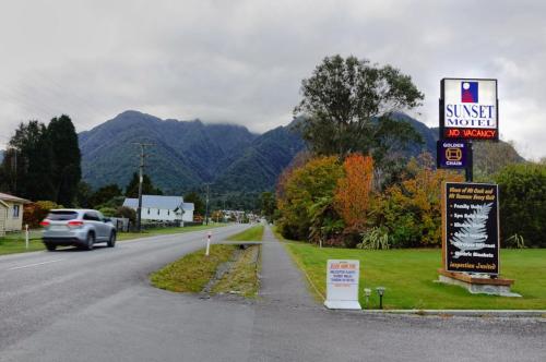 a car driving down a road with mountains in the background at Sunset Motel in Fox Glacier
