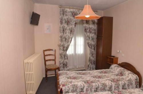 a bedroom with two beds and a chair and a window at Hotel du Commerce in Pont-de-Vaux