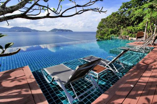 a swimming pool with chairs and a view of the water at Zenmaya Oceanfront Phuket, Trademark Collection by Wyndham in Patong Beach