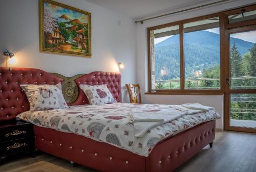 a bedroom with a red bed with a large window at Guest House Milka in Yagodina