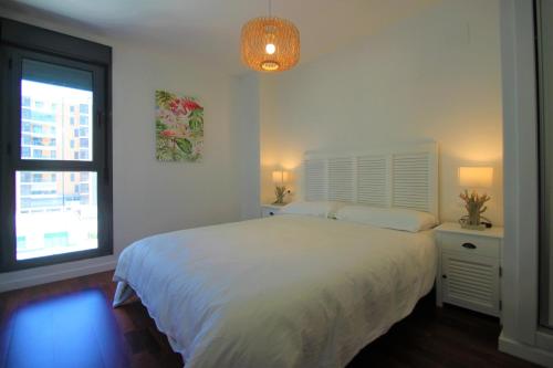 - une chambre avec un lit blanc et une fenêtre dans l'établissement CasaTuris Playa, piscina y parking en Residencial San Juan SJ102, à Alicante