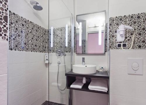 a white bathroom with a sink and a shower at Tourhotel Blois in La Chaussée-Saint-Victor