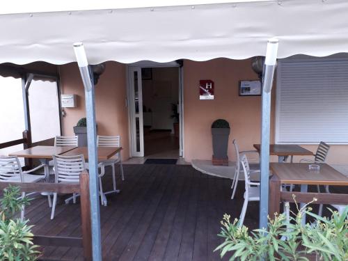 een patio met tafels en stoelen onder een witte tent bij Hotel Le Terminus in Le Lavandou