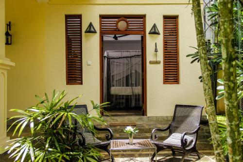 two chairs and a table in front of a house at Good Karma Villa in Bentota