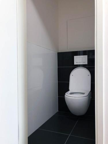 a white toilet in a bathroom with black tiles at Apartment DOWNTOWN in Brno