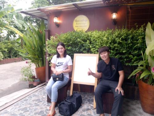 a man and a woman sitting next to a sign at Ruenthip Homestay in Bangkok
