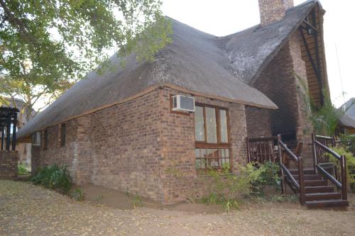 a brick building with a thatched roof with a staircase at Kruger Park Lodge - Golf Safari SA in Hazyview