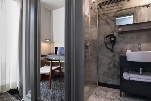 een badkamer met een douche, een wastafel en een bureau bij Nabu Hotel Karaköy in Istanbul