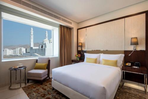 a bedroom with a large bed and a large window at Fraser Suites Muscat in Muscat