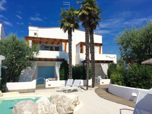 eine Villa mit einem Pool und Palmen in der Unterkunft Marina Village Apartments in Lido di Jesolo