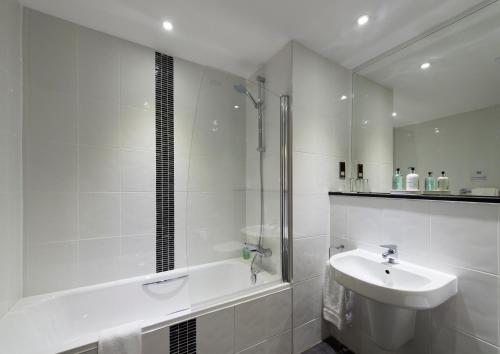 a white bathroom with a sink and a shower at New Lanark Mill Hotel in Lanark